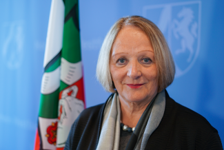 Sabine Leutheusser-Schnarrenberger vor blauem Hintergrund mit der Flagge des Bundeslandes Nordrhein-Westfalen