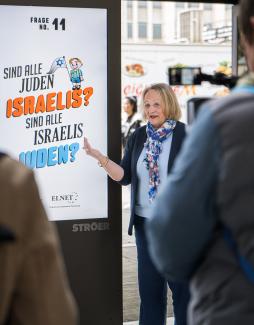 Das Foto zeigt Sabine Leutheusser-Schnarrenberger vor einem Screen, auf dem das Motiv zur Frage „Sind alle Juden Israelis? Sind alle Israelis Juden?“ gezeigt wird.